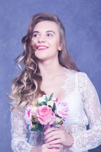 Schöne Braut in einem weißen Peignoir mit einem Strauß Blumen — Stockfoto