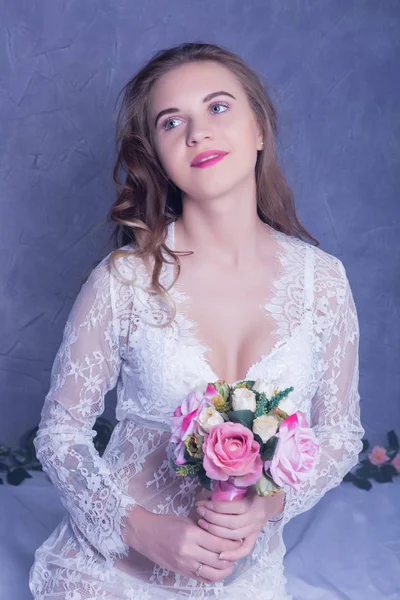 Pengantin cantik di sebuah peignoir putih dengan karangan bunga — Stok Foto