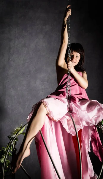 Sexy ragazza eleganza in gonna rosa, oscillante su un'altalena di metallo. aggrapparsi alle catene — Foto Stock