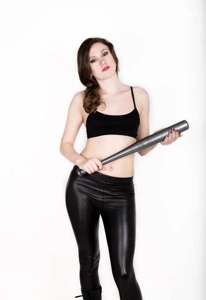Giovane bella donna in pantaloni di pelle e top nero tiene pipistrello da baseball grigio — Foto Stock