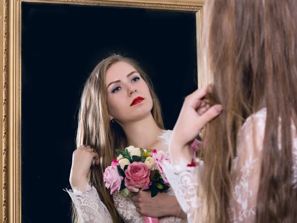 Beauté jeune femme tenant un bouquet de printemps et regarde dans le miroir comme son portrait — Photo