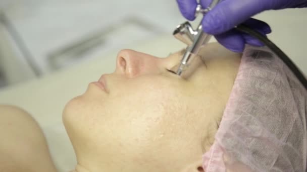 Kosmetolog händer på jobbet, gör ansikte rengöring på en vacker flicka ansikte, rengöring huden med vattenstråle — Stockvideo