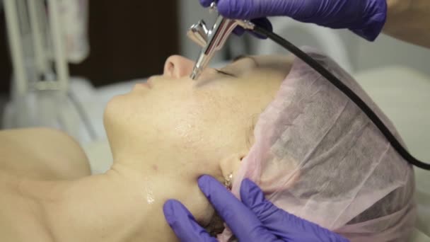 Hermosa mujer recibiendo un tratamiento de medicina cosmética. esteticista haciendo limpieza facial en una hermosa cara de niña, limpieza de la piel con chorro de agua — Vídeos de Stock