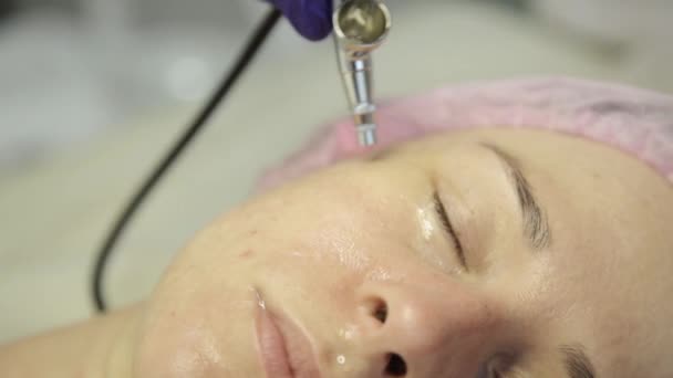Schöne Frau bekommt eine Behandlung der Gesichtshaut. Kosmetikerin macht Gesichtsreinigung auf einem schönen Mädchengesicht und reinigt die Haut mit Wasserstrahl — Stockvideo