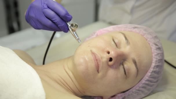 Hermosa mujer recibiendo un tratamiento de medicina cosmética. esteticista haciendo limpieza facial en una hermosa cara de niña, limpieza de la piel con chorro de agua — Vídeos de Stock