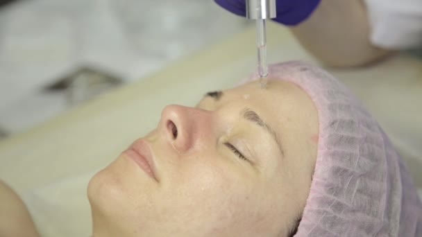 Hermosa mujer recibiendo un tratamiento de la piel facial. esteticista haciendo limpieza facial en una hermosa cara de niña, limpieza de la piel con chorro de agua — Vídeos de Stock