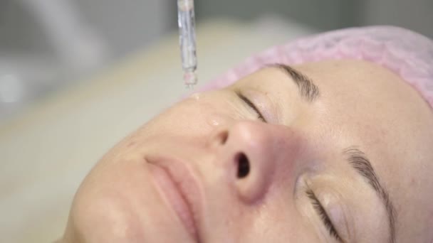 Γκρο πλαν ομορφιάς φροντίδας δέρματος. Cosmetologist ισχύει μια μάσκα του πετρελαίου στο πρόσωπο θηλυκά — Αρχείο Βίντεο