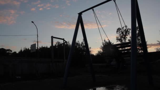 Sad child swinging on a swing on a dark sky background. child abuse, painful childhood — Stock Video