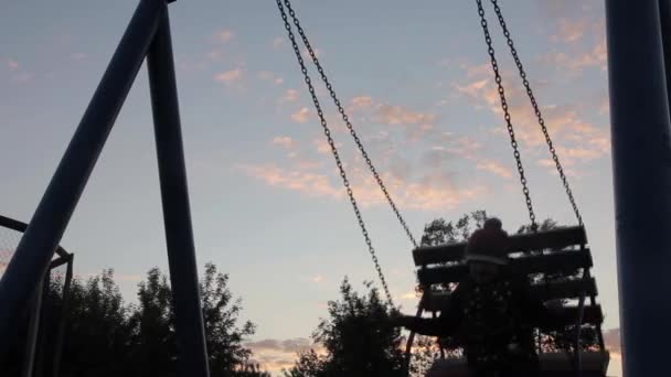 Triste enfant se balançant sur une balançoire sur un fond de ciel sombre. abus d'enfants, enfance douloureuse — Video