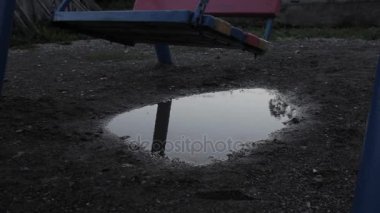 Terk edilmiş Çocuk Bahçesi, salıncakta sallanan masumiyet üzgün çocuk. su birikintileri yansıması.