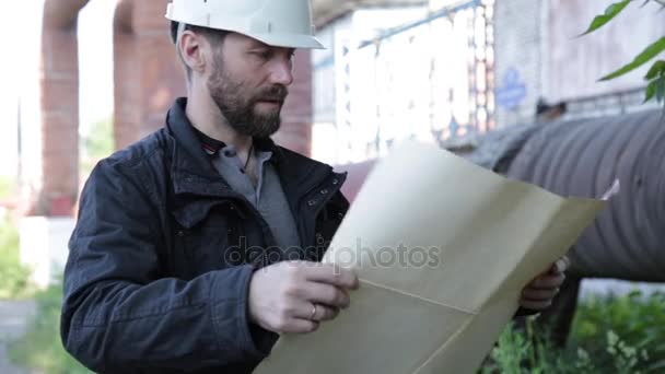 Vedoucí inženýr muž drží to vypadá plán a kontroluje potrubí — Stock video