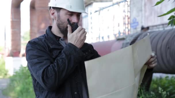 Engineer man supervisor holding blueprints plan and inspects the pipeline — Stock Video