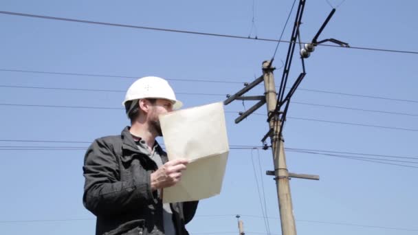 Engenheiro verificar sistemas elétricos falar walkie-talkie, Inspector segurando plano de plantas — Vídeo de Stock