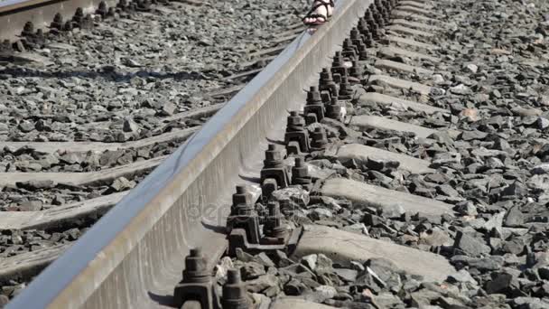 Bela mulher andando ao longo das trilhas ferroviárias em um dia de sol — Vídeo de Stock