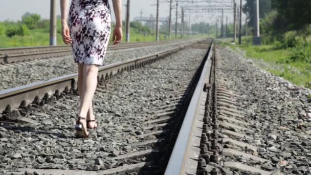 Красивая женщина, идущая вдоль железнодорожных путей в солнечный день — стоковое видео