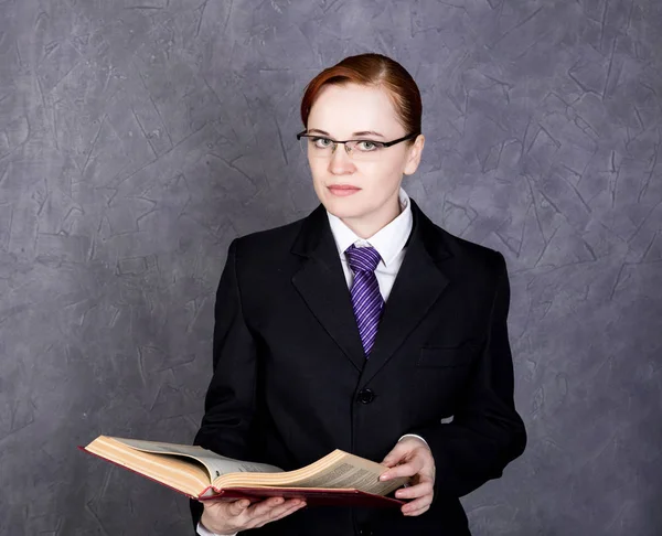 Advogada feminina segurando um grande livro com expressão séria, mulher em um terno homem, gravata e óculos — Fotografia de Stock