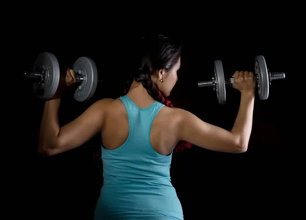 Фитнес-молодая женщина на тренировке с гантелями на черной пекарне, спортивная мускулистая брюнетка — стоковое фото