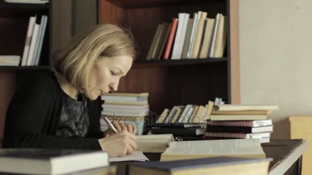 Üniversiteler kitaplığında kitaplar ile çalışan kız öğrenci odaklı. yorgun öğrenci sınavlara hazırlama — Stok video