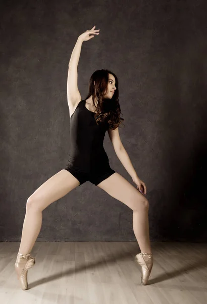 Joven hermosa bailarina de ballet en zapatos de punta, bailando en un fondo oscuro — Foto de Stock