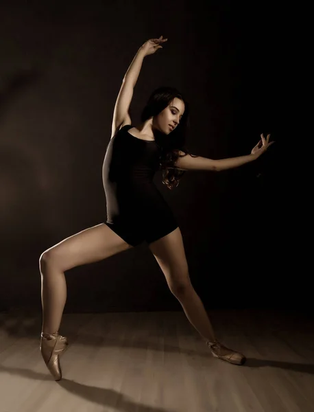 Jovem bela dançarina de balé em sapatos pontiagudos, dançando em um fundo escuro — Fotografia de Stock