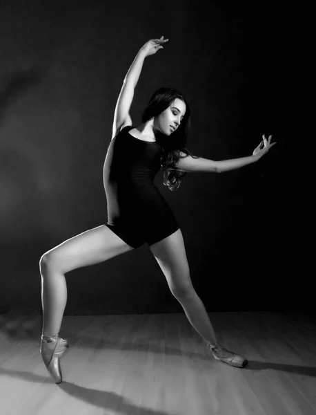 Giovane bella ballerina di balletto in scarpe da punta, ballando in uno sfondo scuro. bianco e nero — Foto Stock