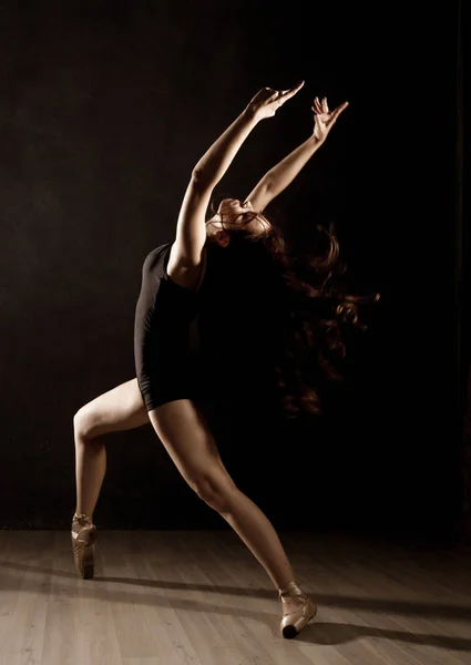 Jeune belle danseuse de ballet en pointes, dansant dans un fond sombre — Photo