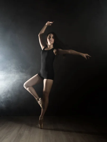 Joven hermosa bailarina de ballet en zapatos de punta, bailando en un humo sobre un fondo oscuro . — Foto de Stock