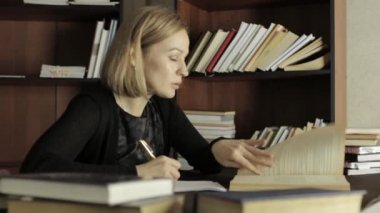 genç kadın doktora masada oturan bir ders için hazırlanıyor ve gerekli bilgi kitap yazıyor
