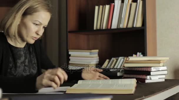 Vrouwelijke docent werken met boeken in een bibliotheek op de Universiteit. moe studenten voorbereiden op examens — Stockvideo