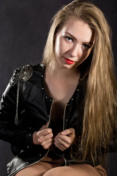 Beautiful young woman in a leather jacket posing on a gray background — Stock Photo, Image