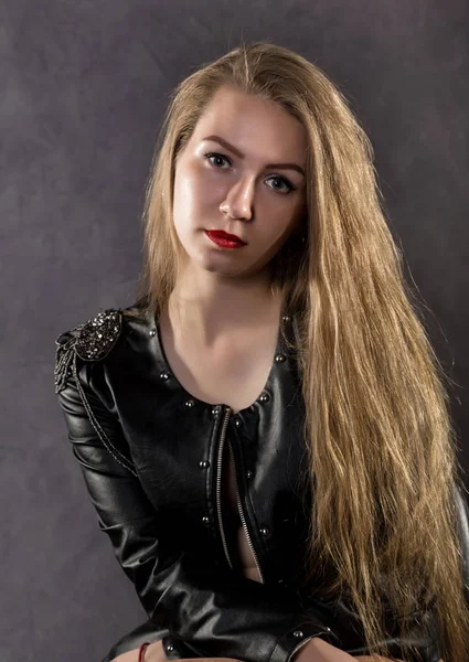 Schöne junge Frau in Lederjacke posiert auf grauem Hintergrund — Stockfoto