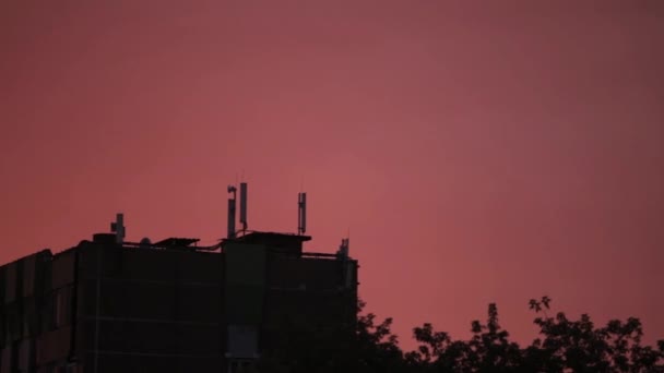 Heldere oranjerode zon opkomt over gebouw, electro transmissielijnen, telecommunicatie antennes en bomen. — Stockvideo