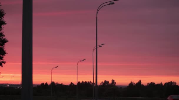 Heldere oranjerode zon opkomt over weg, electro transmissielijnen, gebouwen en bomen. — Stockvideo