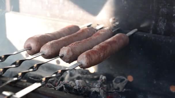 Utendørs grillfest. Smaker saftige pølser grillet over en brann – stockvideo