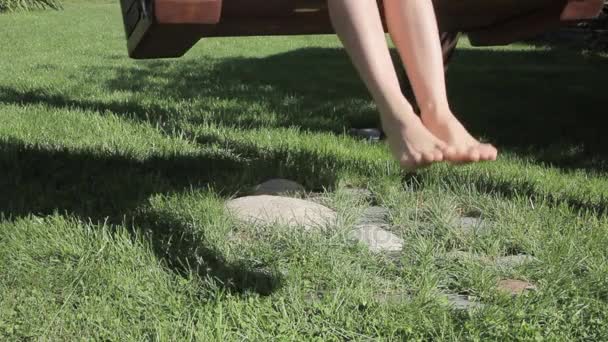 Fille sur une balançoire, seulement les jambes et l'ombre — Video