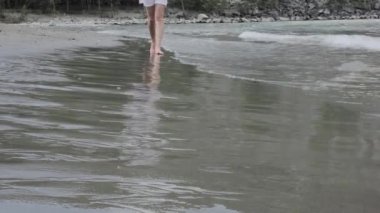 Genç kadın sakin sörf kumsalda yürür.