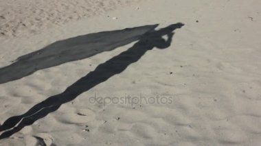 Bir rüzgar üzerinde pareo ile ince genç kız bir kum üzerine gölge