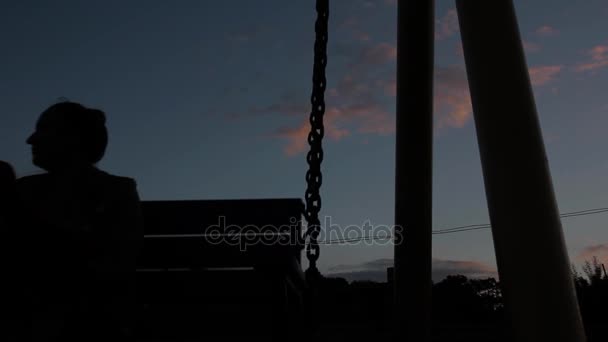 Mujer triste balanceándose sobre un columpio sobre un fondo de cielo oscuro. abuso de mujeres — Vídeo de stock