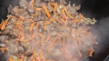 Kuzu ile pilav pişirme, havuç ve baharatlarla soğan bir ahşap üzerine bir kazan içinde soba