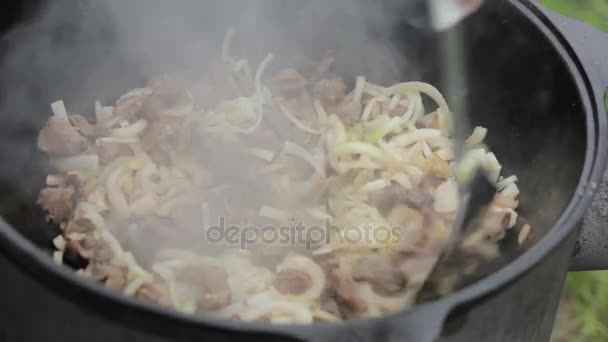 Cocción de pilaff con cordero y cebolla en un caldero en una estufa de leña — Vídeo de stock