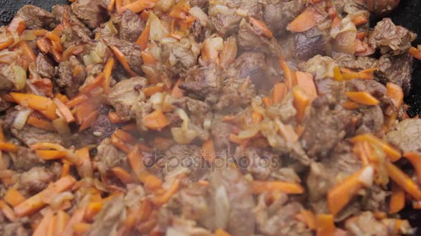 Cooking of pilaff with lamb, carrots and spices onions in a cauldron on a wood stove — Stock Video