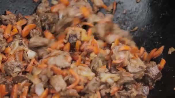 Cocción de pilaff con cordero, zanahorias y especias cebollas en un caldero en una estufa de leña — Vídeos de Stock