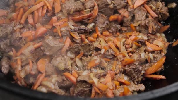 Cooking of pilaff with lamb, carrots and spices onions in a cauldron on a wood stove — Stock Video