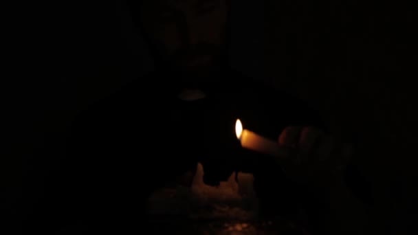 Католический викарий зажигает свечи и читает из Священной Библии в темноте — стоковое видео