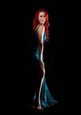Mavi şık elbiseli genç Kızıl saçlı seksi kadın bir karanlıkta teşkil etmektedir.