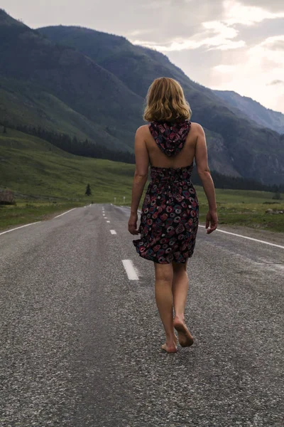 Mujer sola descalza está caminando a lo largo de la carretera de montaña. Concepto de viajes, turismo y personas — Foto de Stock
