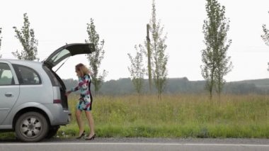 sarışın kız kırık arabası ile açık bir ülke yolunda gövdede yakınındaki bir panik içinde cep telefonu arama