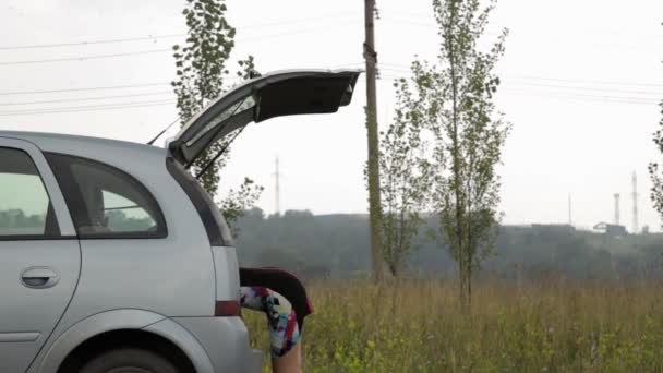 Бідна жінка відкриває багажник і бере інструменти. Жіночий водій, аварійні та водійські проблеми, розчарована дівчина з плоскою шиною — стокове відео