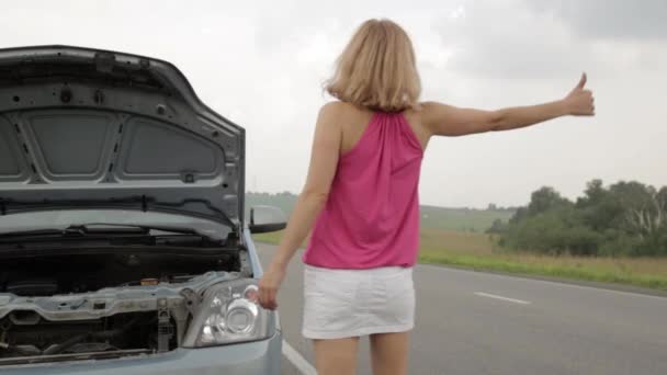 Schöne Frau fängt ein Auto in der Nähe eines kaputten Autos. Fahrerin hatte Probleme mit Auto, Notsituation — Stockvideo