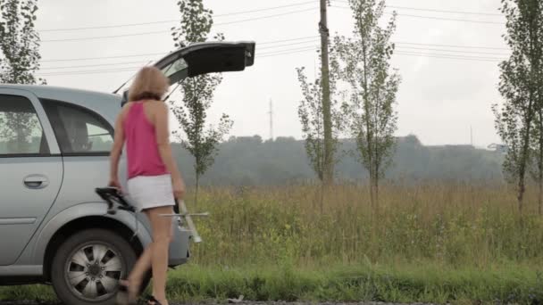 Oszołomiony kobieta otwiera tułowia i bierze narzędzia. Kobieta-kierowca, awaryjne i jazdy problemy, dziewczynka z płaskim samochodu opony — Wideo stockowe